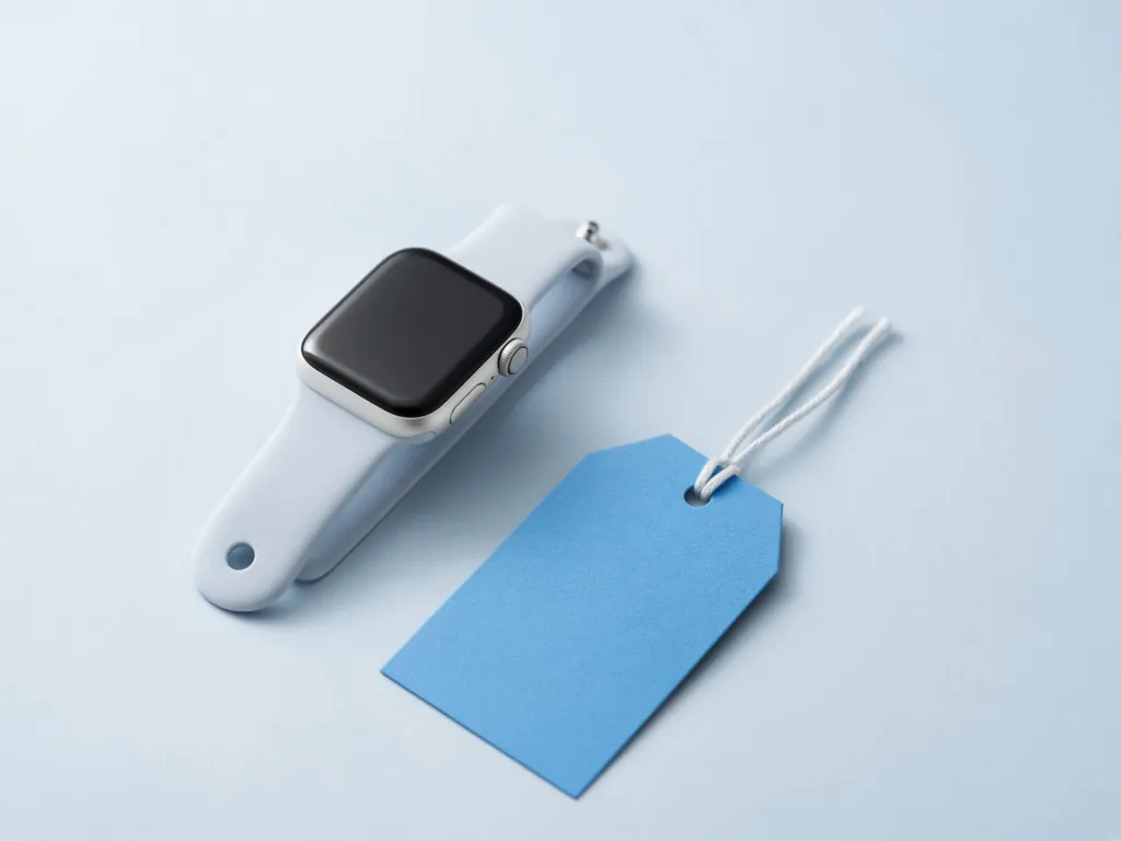 Apple Watch beside a blue shopping price tag on a light surface